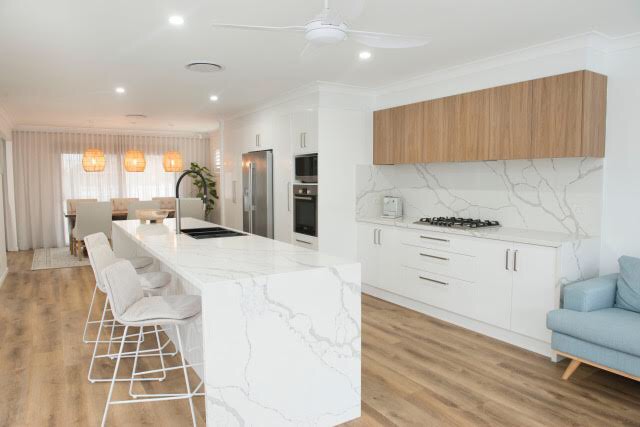 Long marble-look island with stools and timber overhead cabinets