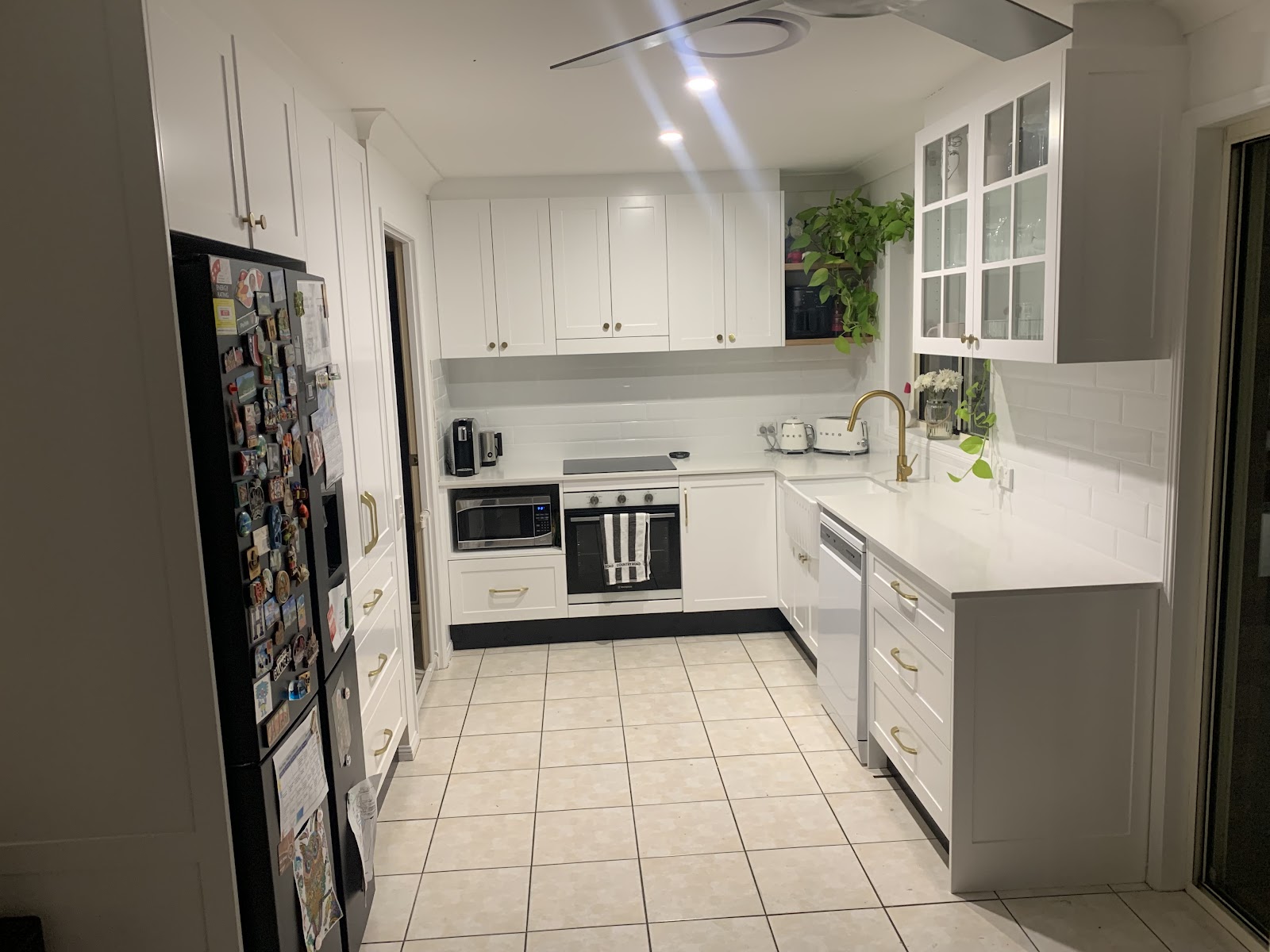White Shaker kitchen with brass handles, a butler sink and a glass-door cabinet