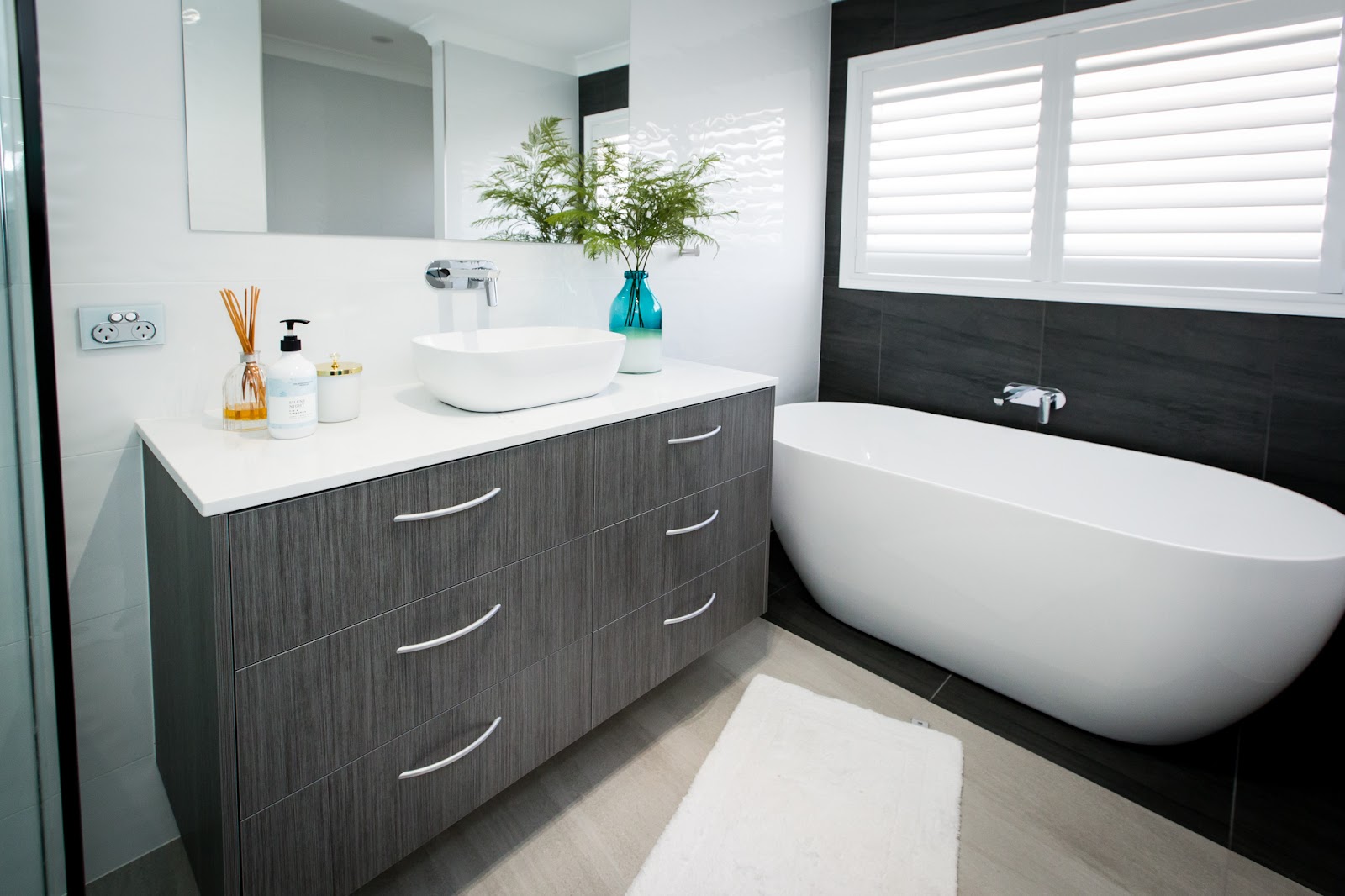 Floating woodgrain bathroom vanity with a white stone top, vessel basin and freestanding bath